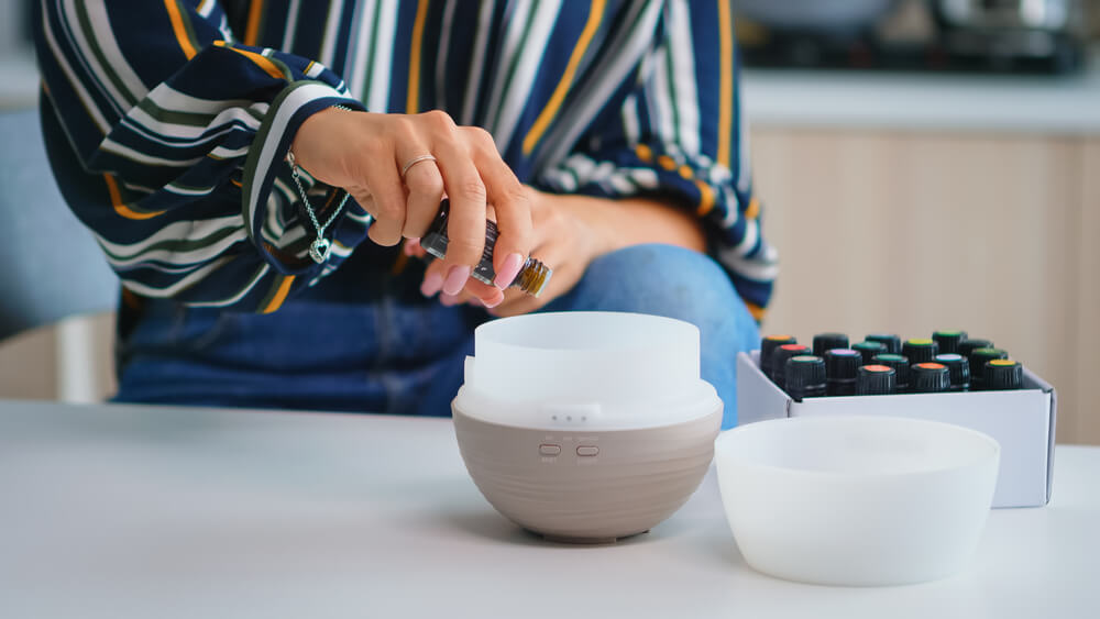 Woman putting oil into diffuser