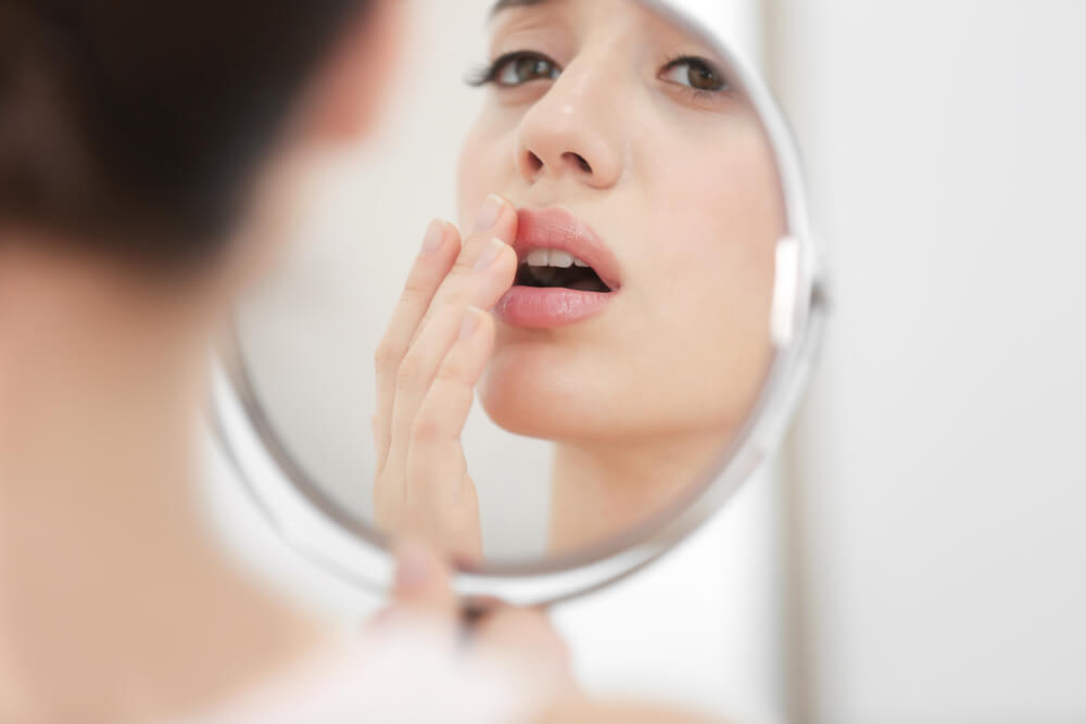 Woman looking at lips in mirror